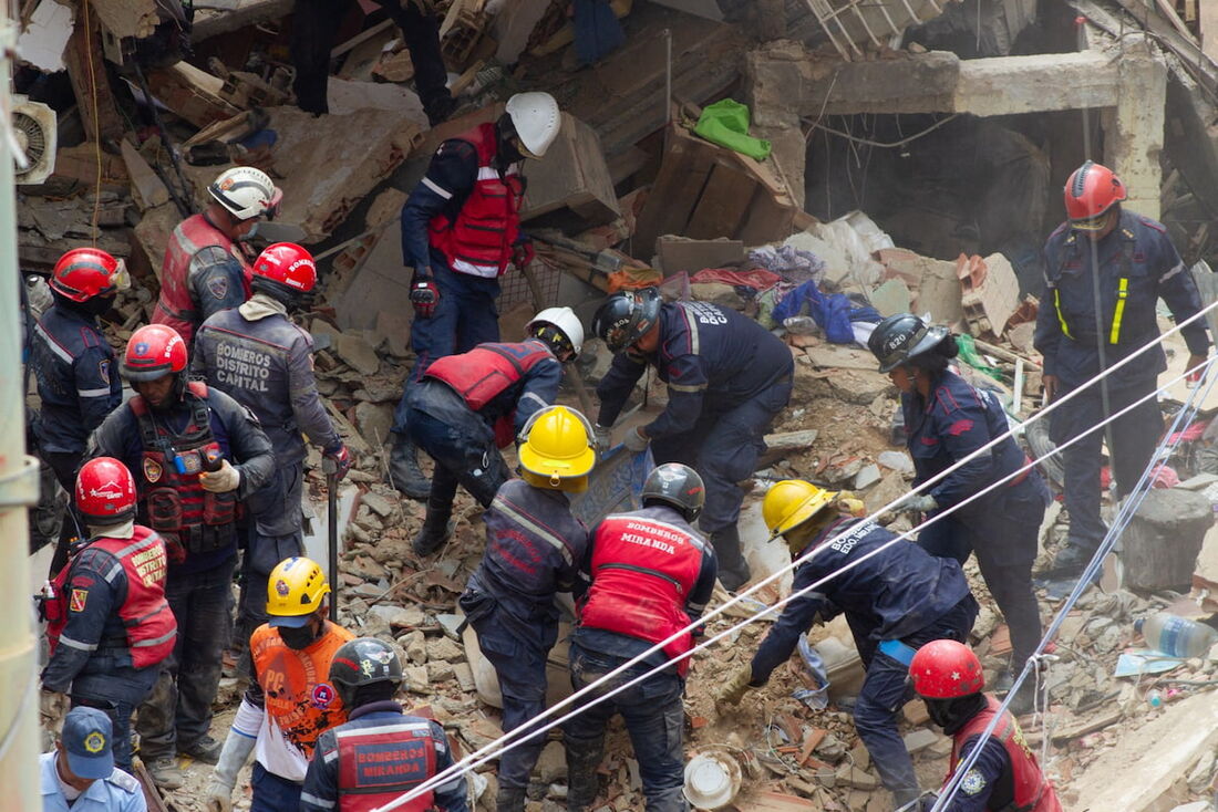 Bombeiros removem destroços de uma casa destruída por uma explosão após um vazamento de gás no bairro Union em Petare, Caracas