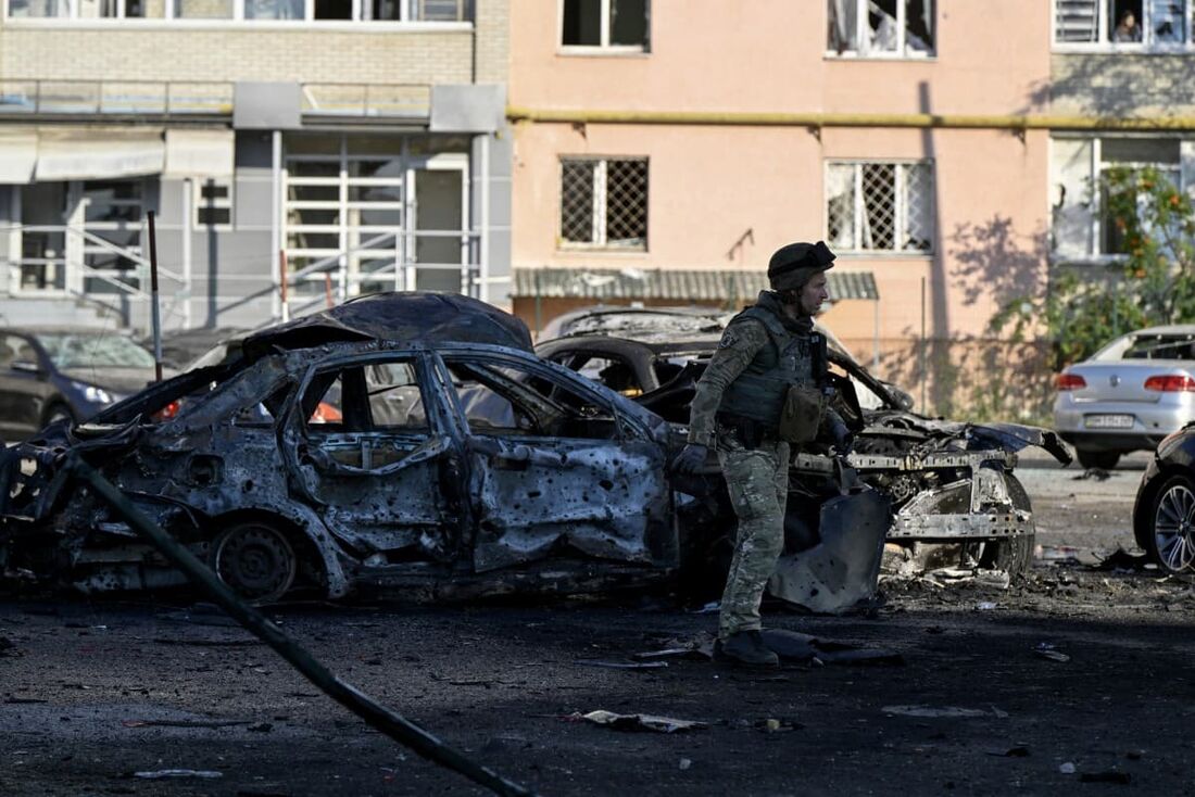 Um especialista da polícia passa por carros queimados no local de um ataque russo na cidade de Sumy em 17 de agosto de 2024, em meio à invasão russa da Ucrânia