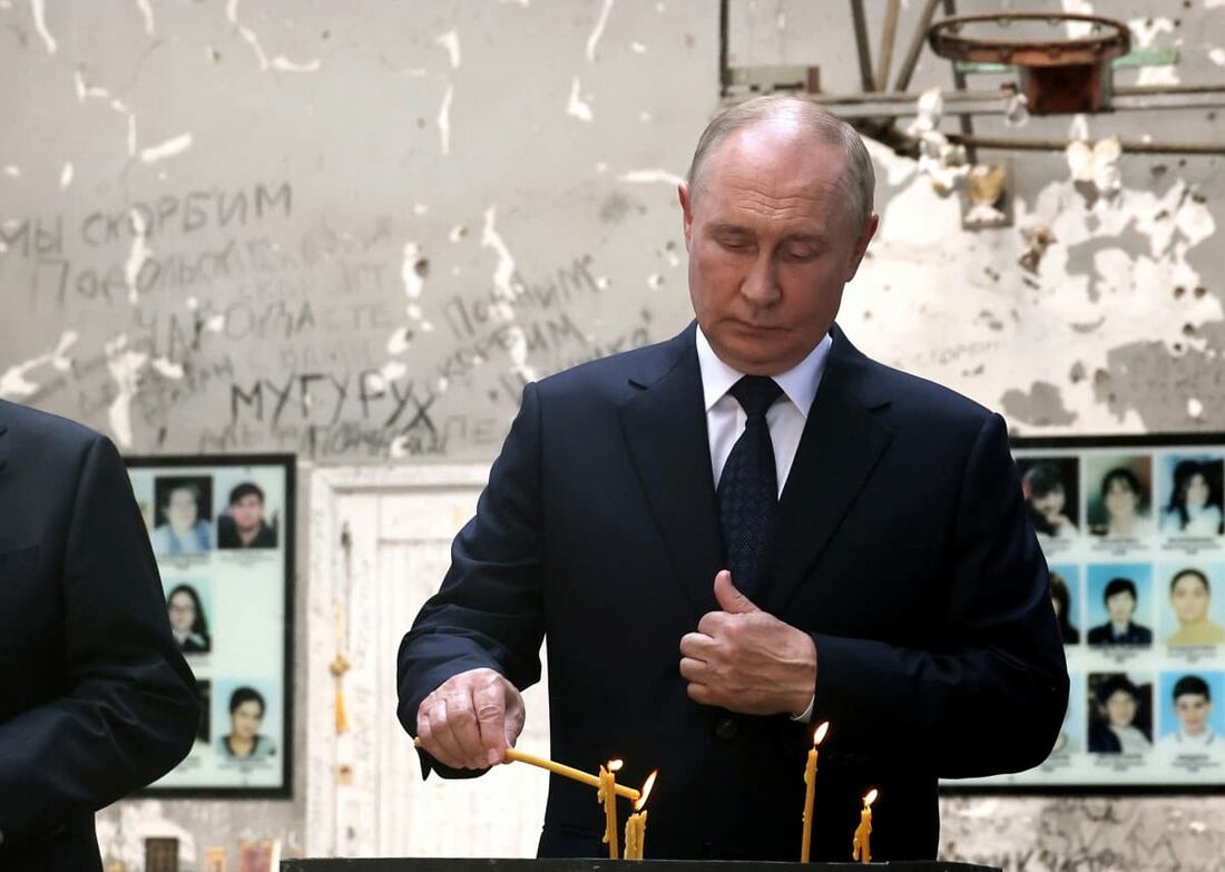 O presidente russo Vladimir Putin acende uma vela no local da escola destruída, onde em 2004 militantes chechenos fizeram mais de 1.000 pessoas como reféns