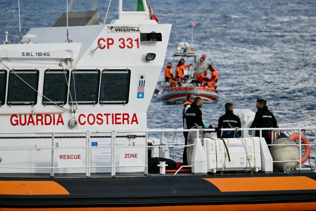 Guardas costeiros italianos carregam um corpo em um barco de resgate no porto de Porticello, perto de Palermo, com um terceiro corpo na parte de trás do barco em 21 de agosto de 2024