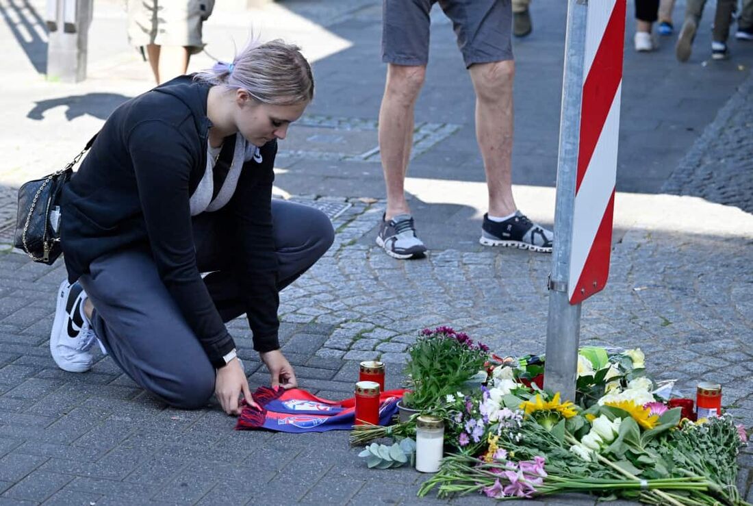 Mulher se ajoelha em um memorial improvisado de flores e velas para as vítimas do ataque a facadas na Alemanha