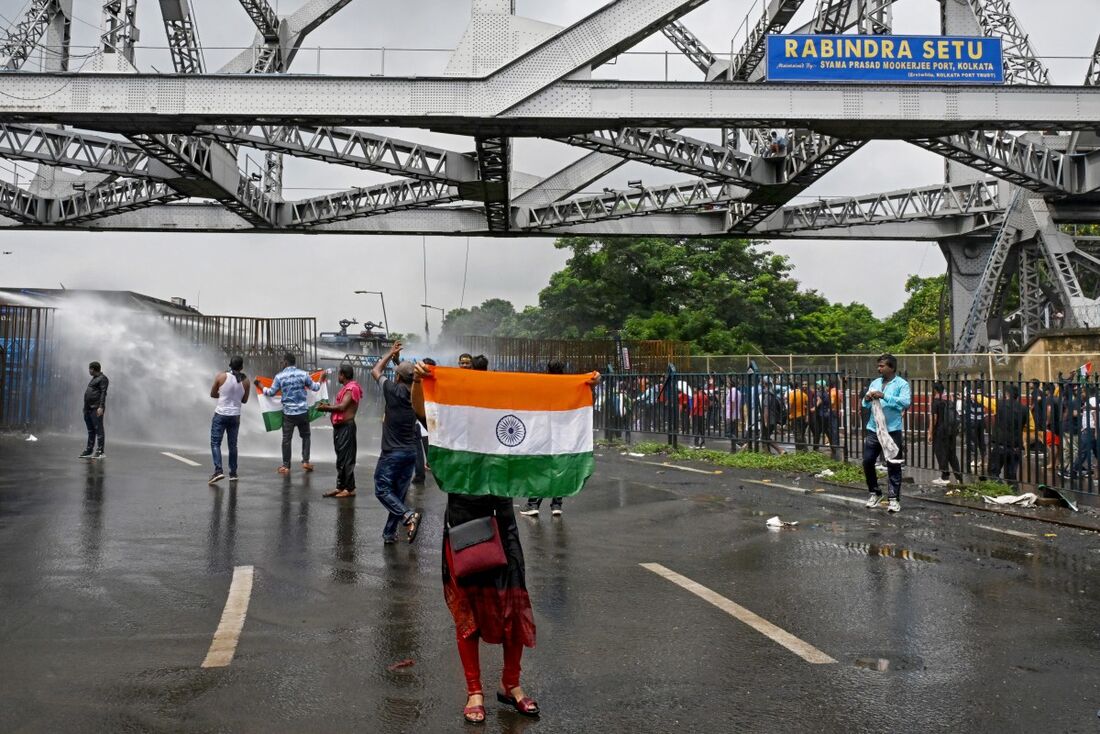 A polícia usa canhões de água para dispersar ativistas carregando a bandeira nacional da Índia enquanto marcham em direção à secretaria de estado exigindo a renúncia de Mamata Banerjee, ministra-chefe do estado de Bengala Ocidental