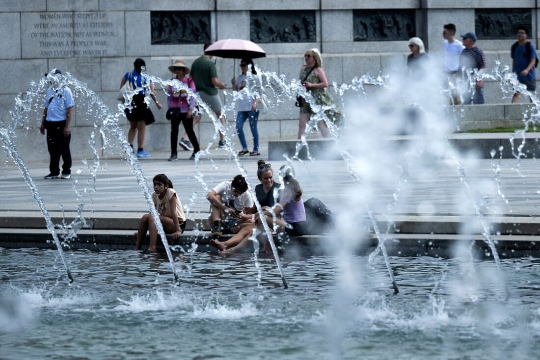 Pessoas descansam os pés em um espelho d'água no Memorial da Segunda Guerra Mundial no National Mall em Washington, DC