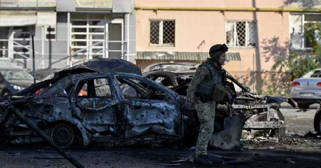 Militar passa por carros queimados no local de um ataque russo na cidade de Sumy em 17 de agosto de 2024, em meio à invasão russa da Ucrânia