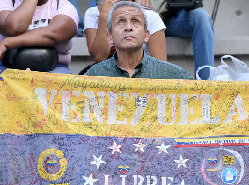 Homem segura bandeira da Venezuela durante vigília convocada pela oposição exigindo liberdade para os presos políticos detidos em protestos contra Nicolás Maduro