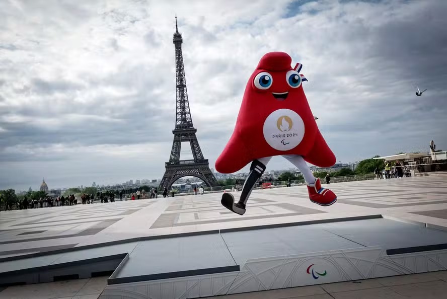 Phryge, a mascote oficial dos Jogos Paralímpicos de Paris 2024, salta no pódio colocado diante da Torre Eiffel 