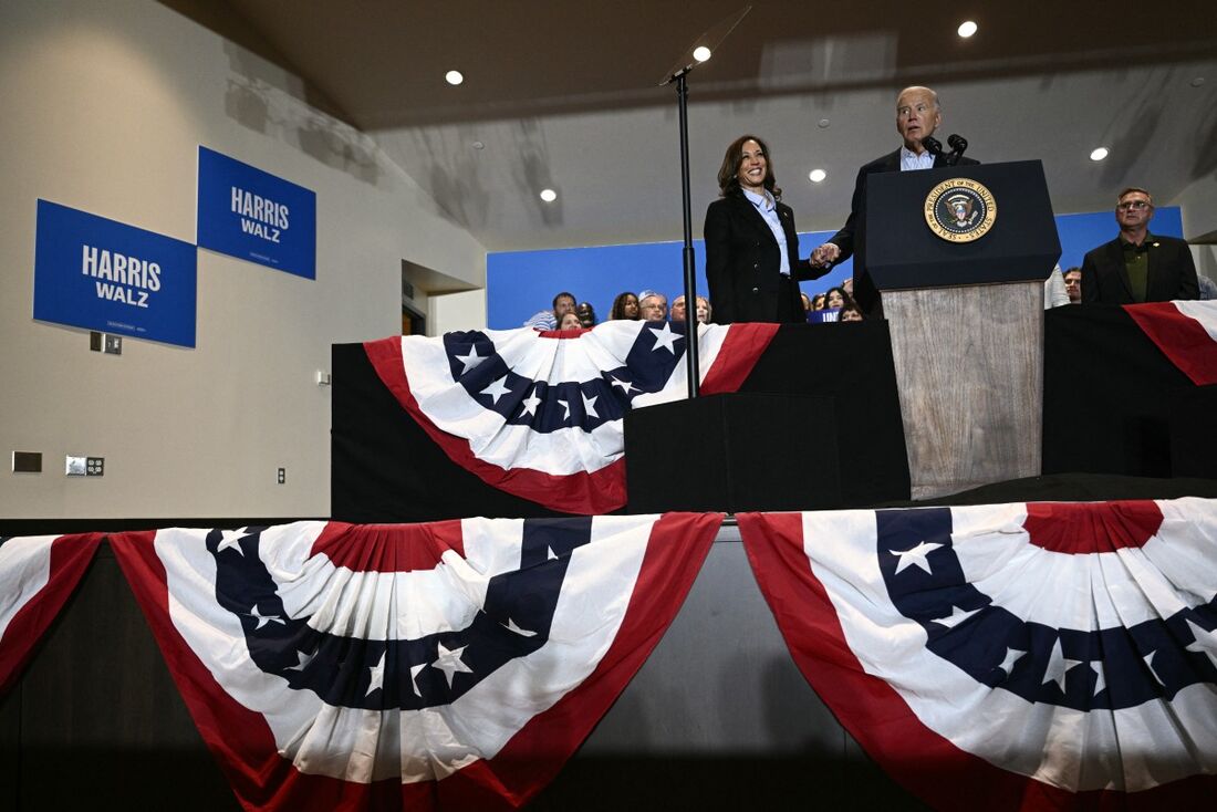 A vice-presidente dos EUA e candidata presidencial democrata Kamala Harris (E) segura as mãos do presidente dos EUA Joe Biden enquanto ele discursa durante um comício de campanha em Pittsburgh, Pensilvânia