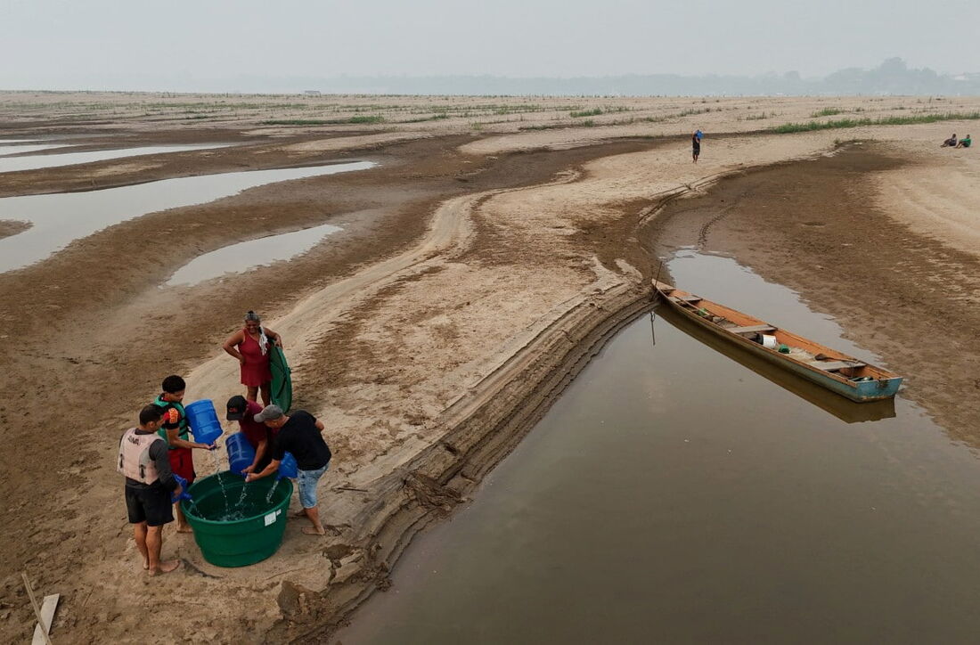 Homens coletam água potável próximo a um banco de areia do Rio Madeira na Comunidade de Paraizinho, em Humaitá, estado do Amazonas