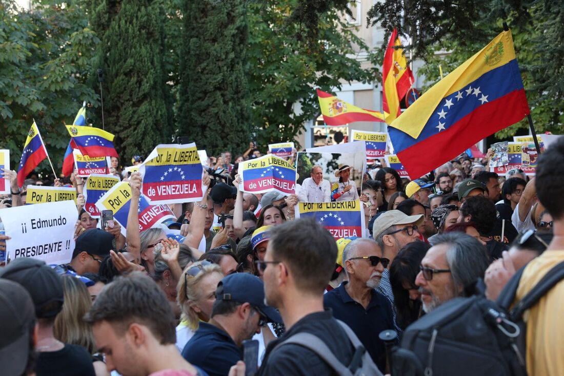 Apoiadores da oposição venezuelana seguram cartazes com os dizeres "Pela liberdade da Venezuela" enquanto se manifestam em frente ao Parlamento espanhol