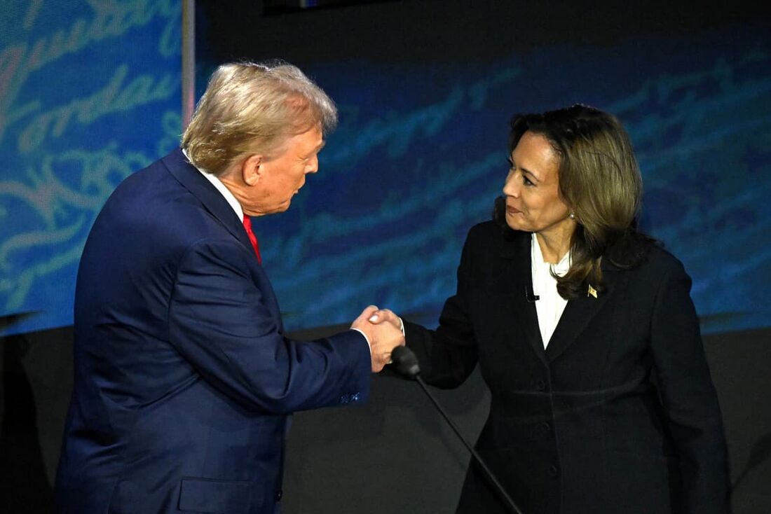 Candidata presidencial democrata Kamala Harris (D) aperta a mão do ex-presidente dos EUA e candidato presidencial republicano Donald Trump