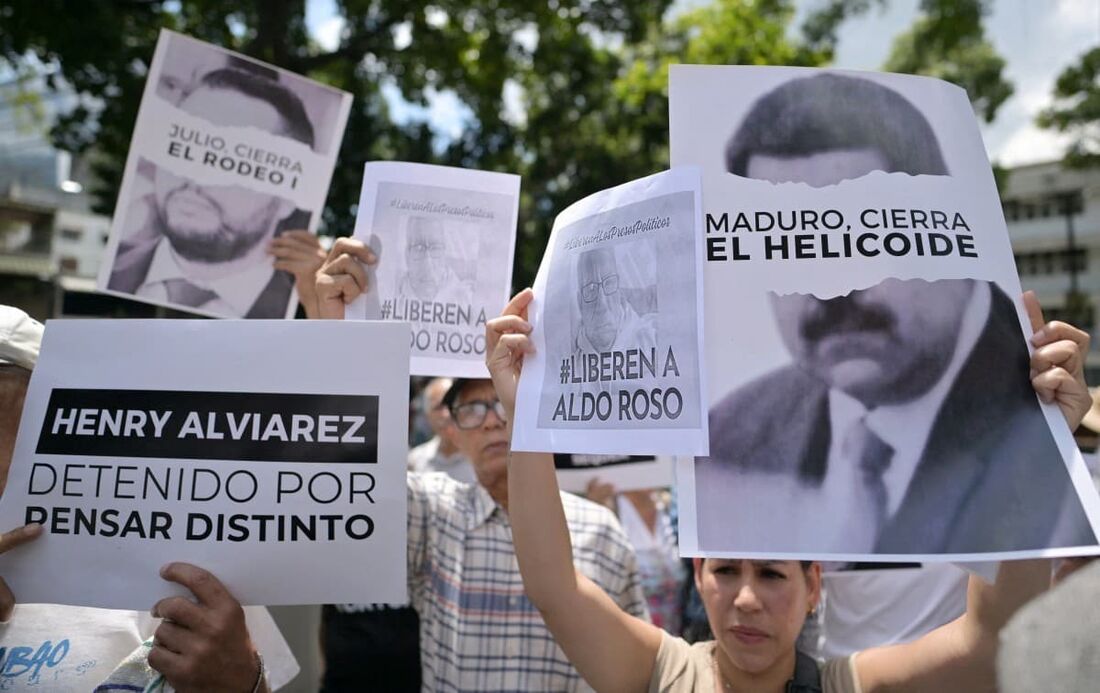 Manifestantes seguram cartazes contra o governo do presidente Nicolás Maduro e exigem liberdade para presos políticos