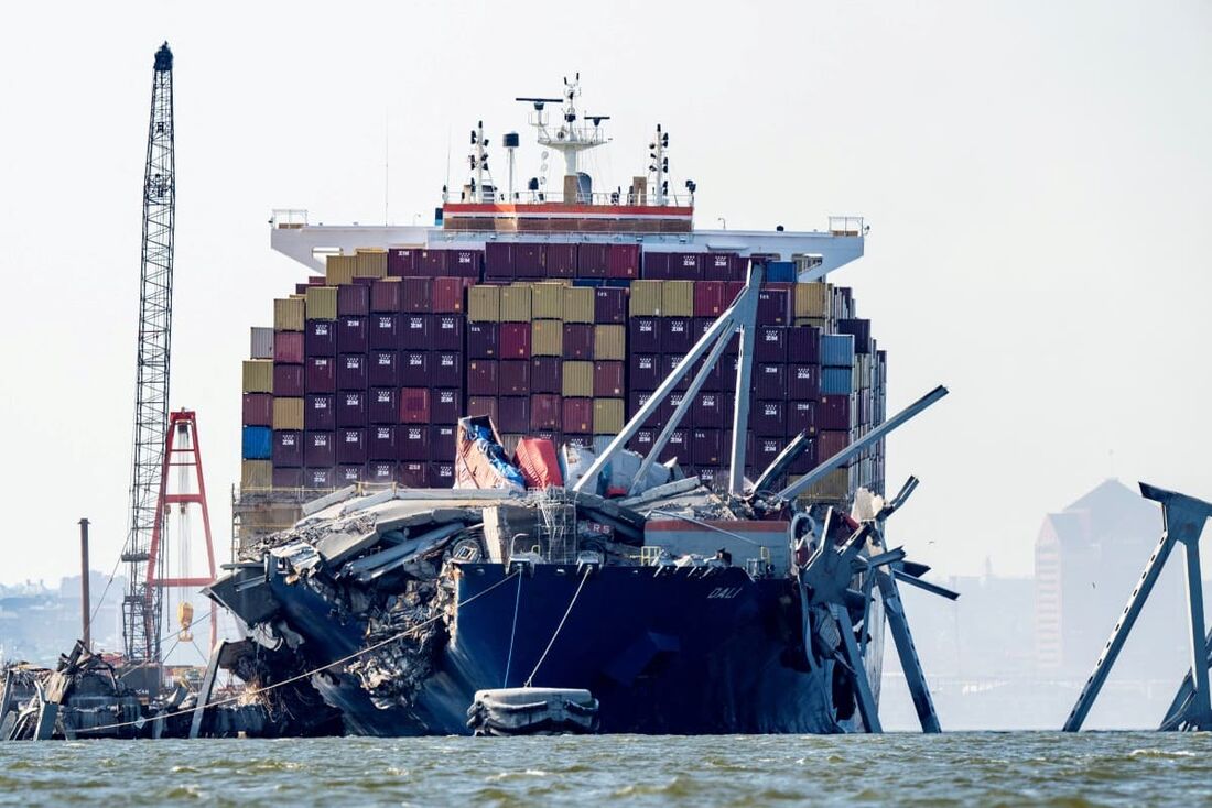 Uma seção da Francis Scott Key Bridge repousa na água ao lado do navio porta-contêineres Dali em Baltimore em 13 de maio de 2024, após as equipes realizarem uma demolição controlada.