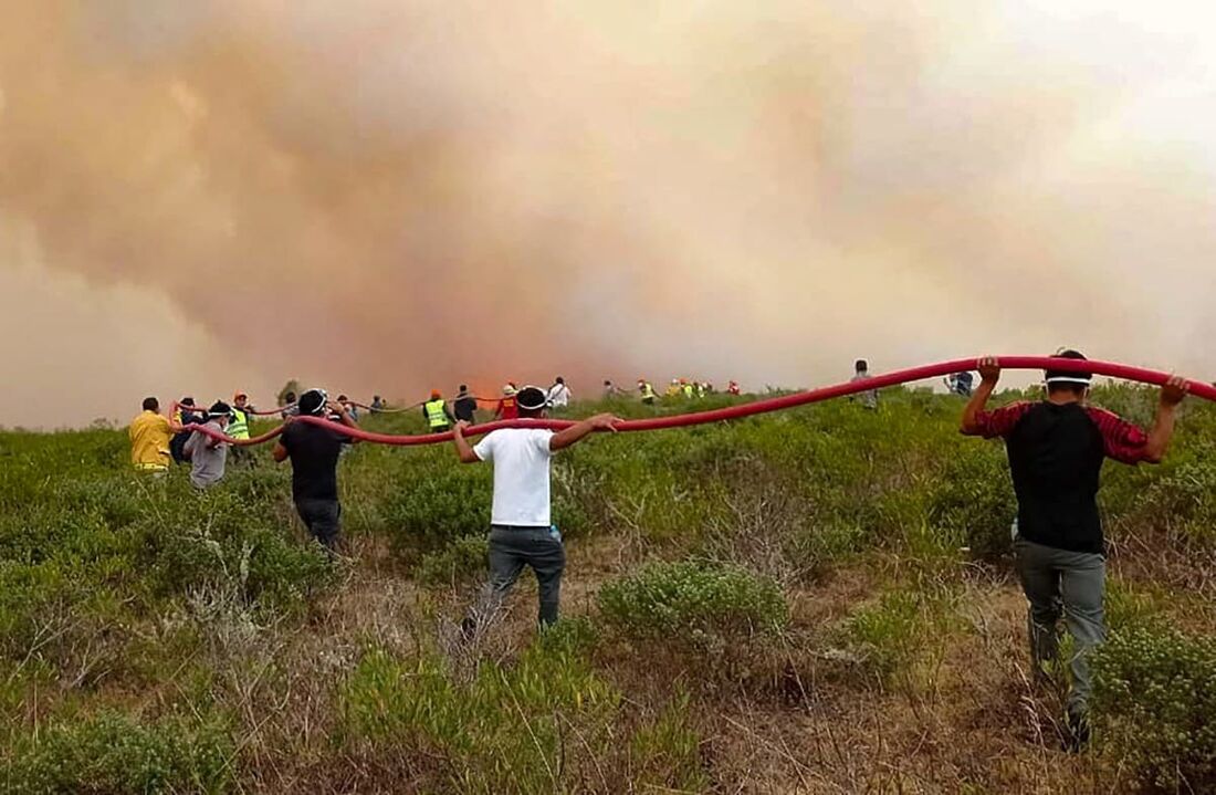 Membros da Defesa Civil, bombeiros e voluntários tentando extinguir um incêndio florestal que afeta o território na Região Amazônica no norte do Peru