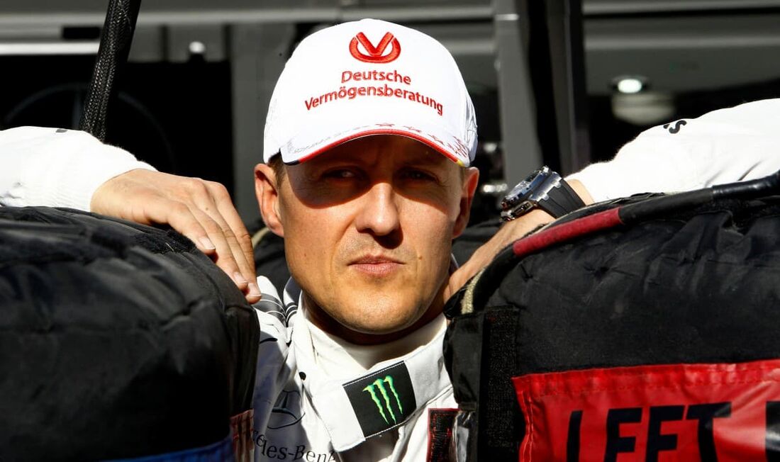 Nesta foto de arquivo tirada em 22 de novembro de 2012, o então piloto alemão de Fórmula 1 Michael Schumacher se inclina entre dois pneus na pista de corrida de Interlagos, em São Paulo, Brasil. 