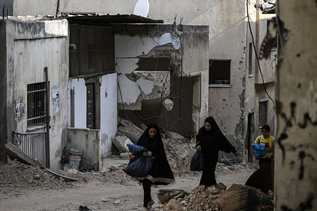 Moradores caminham em meio à destruição após um ataque militar israelense no campo de refugiados de Jenin, na Cisjordânia ocupada