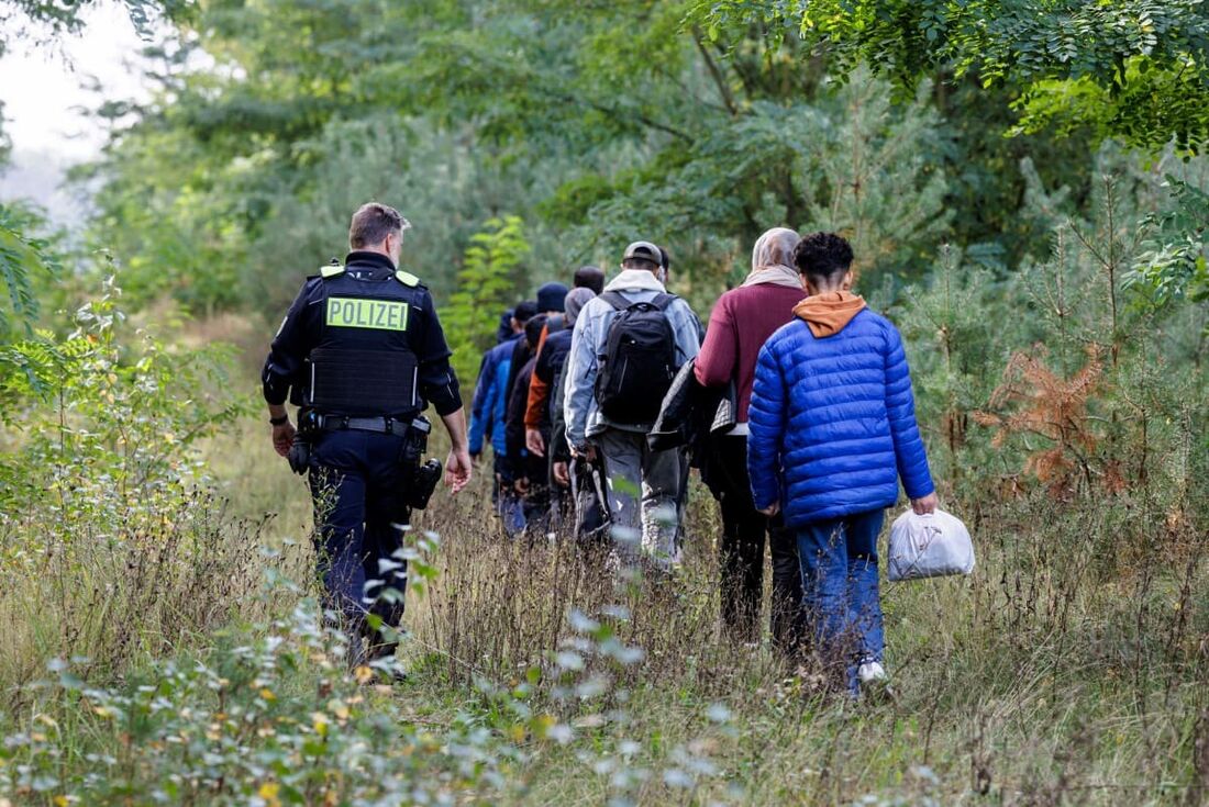 Um oficial da Polícia Federal Alemã (Bundespolizei) escolta um grupo de migrantes perto de Forst, no leste da Alemanha