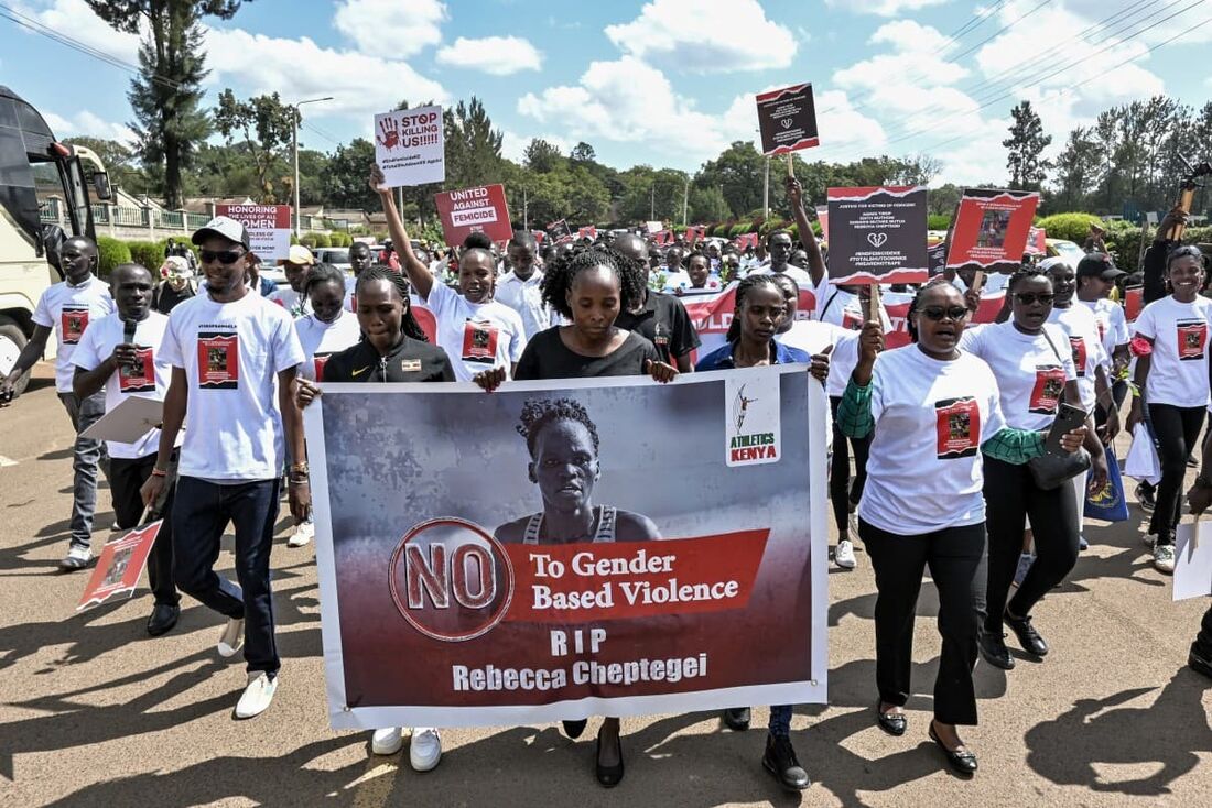 Ativistas e atletas carregam uma faixa enquanto marcham por Eldoret, oeste do Quênia, em 13 de setembro de 2024, para protestar contra o assassinato de mulheres no Quênia depois que Rebecca Cheptegei perdeu a vida.