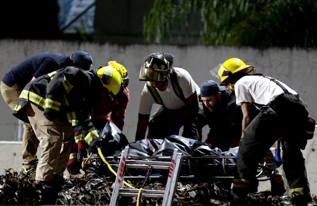 Um grupo de bombeiros, ao lado de peritos forenses e membros do Ministério Público, recuperam um dos três corpos amarrados dentro dos vagões de um trem que cruza Guadalajara, estado de Jalisco, México