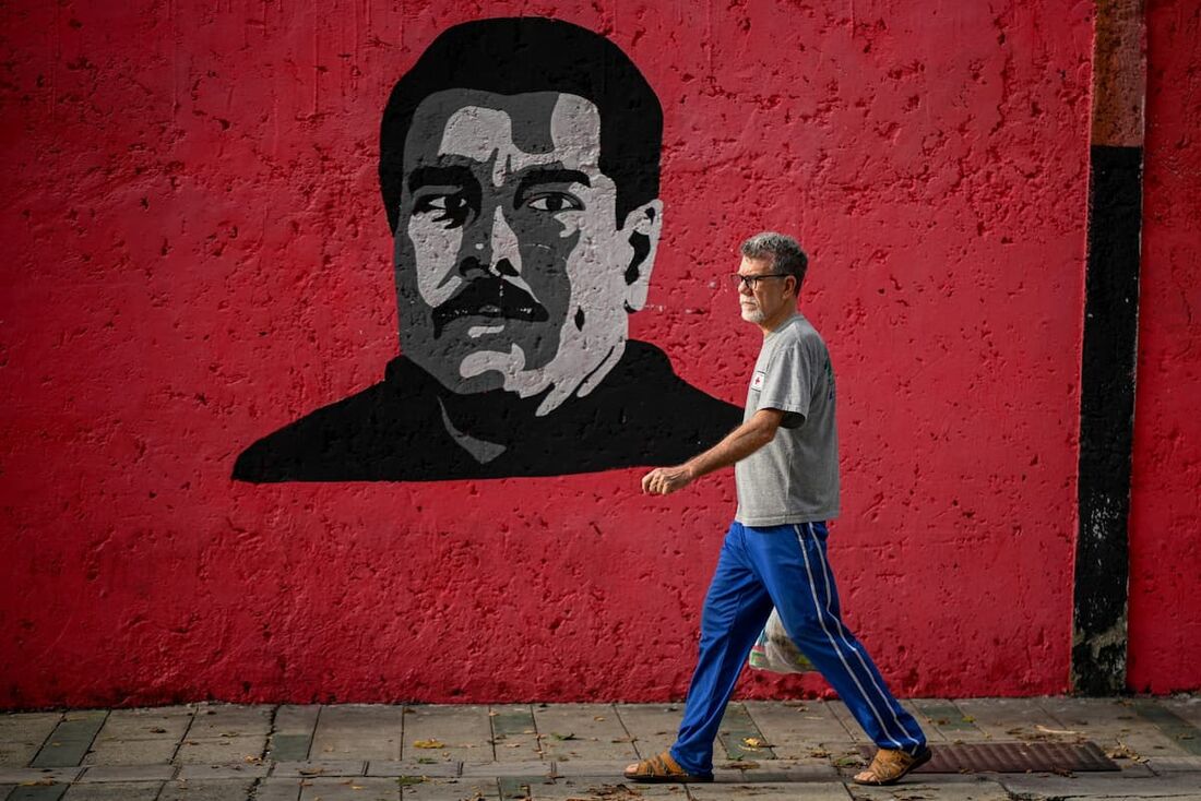 Um homem passa por um mural representando o presidente venezuelano Nicolás Maduro em Caracas