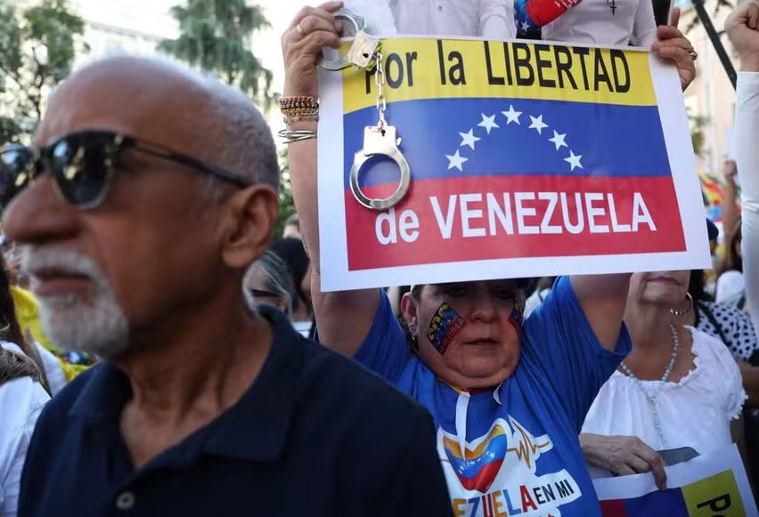 Um apoiador da oposição venezuelana segura uma placa com os dizeres 'Pela liberdade da Venezuela' enquanto se reúnem em frente ao Parlamento Espanhol 