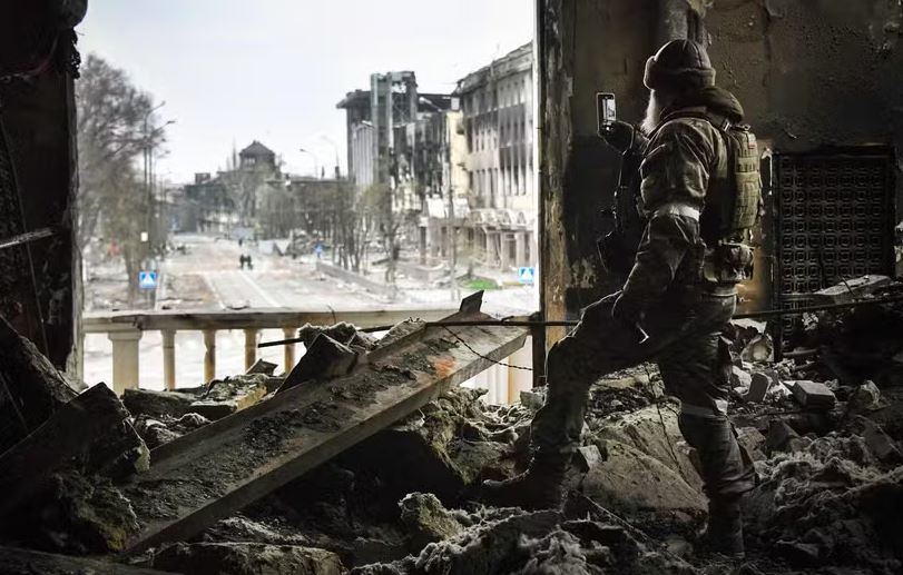 Militar russo tira foto dos escombros do teatro de Mariupol, no leste da Ucrânia 