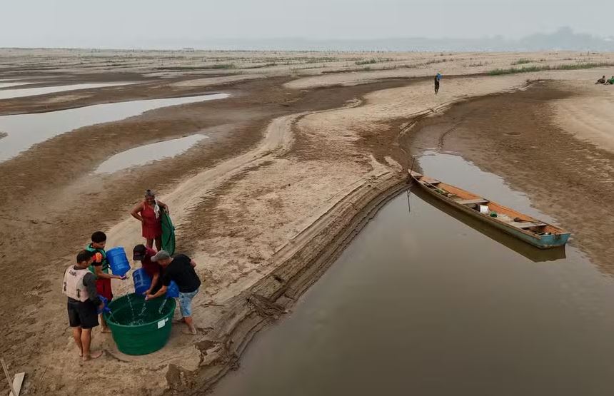 Moradores coletam água potável ao lado de banco de areia no rio Madeira, no estado do Amazonas, que sofre com os efeitos da seca 