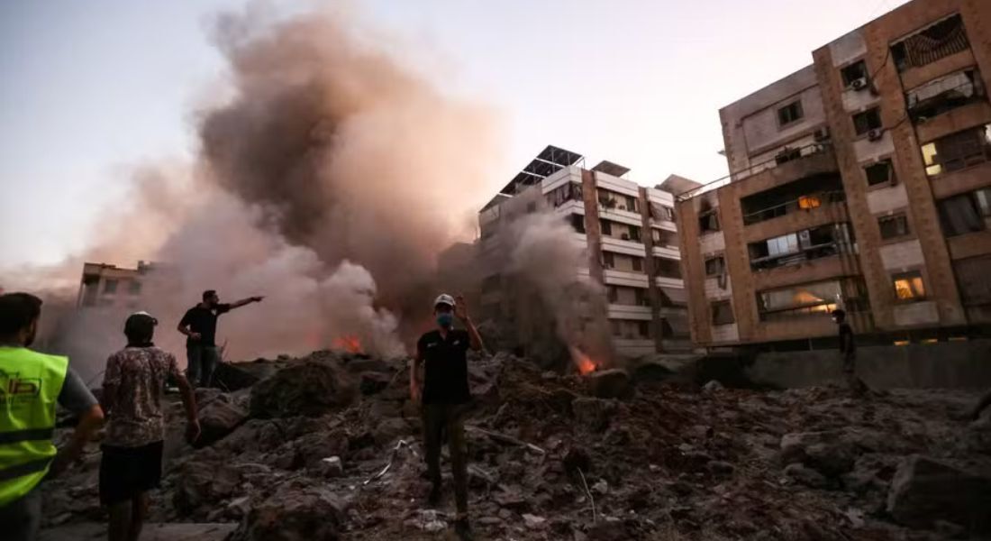 Pessoas e equipes de resgate em meio aos escombros de um prédio destruído em um ataque aéreo israelense no bairro de Haret Hreik, nos subúrbios ao sul de Beirute, em 27 de setembro de 2024