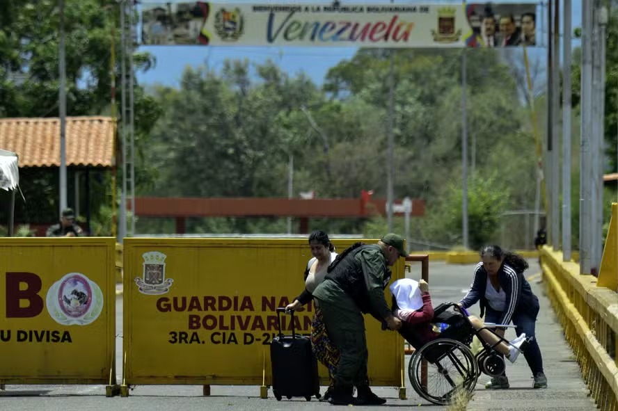 Mulher venezuelana em uma cadeira de rodas é ajudada por um membro da Guarda Nacional Venezuelana na ponte internacional Simon Bolivar após o fechamento da fronteira Colômbia-Venezuela 