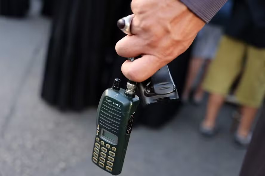 Homem segura walkie-talkie com a bateria removida durante o funeral de pessoas mortas na explosão de pagers, na terça-feira, no Líbano 