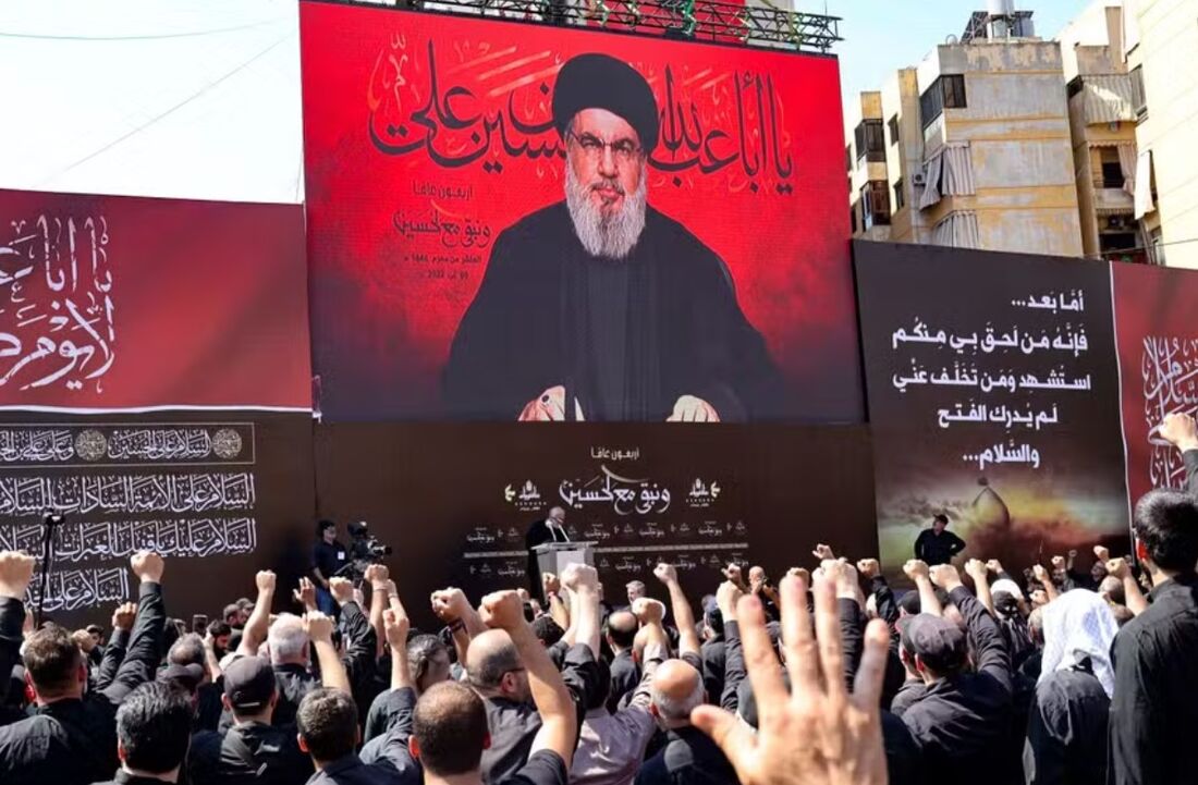 Apoiadores do Hezbollah do Líbano reagem enquanto o líder do grupo, Hassan Nasrallah, se dirige a eles por meio de uma tela gigante nos subúrbios ao sul de Beirute, em 9 de agosto de 2022 