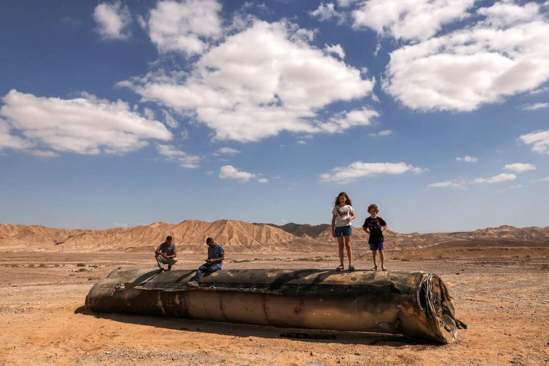 Pessoas em cima dos restos de um míssil iraniano no deserto de Negev, perto de Arad, em 2 de outubro de 2024, após um ataque de míssil iraniano contra Israel.