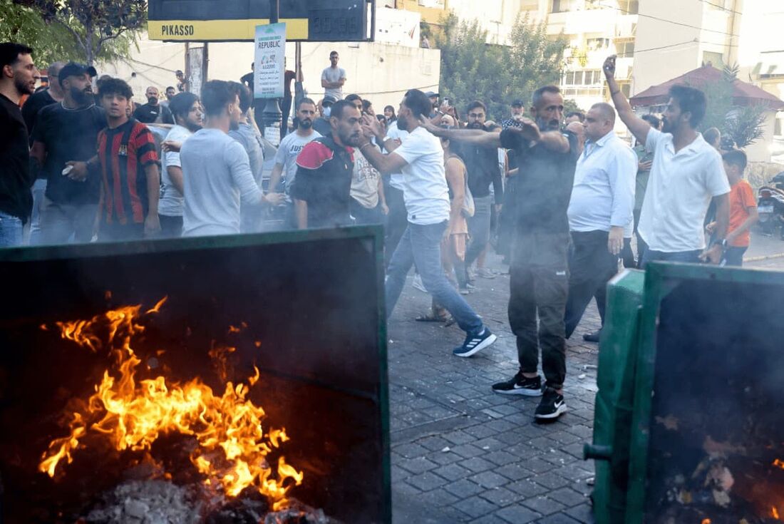 Pessoas deslocadas que fugiram do bombardeio israelense nos subúrbios ao sul de Beirute acendem fogo enquanto entram em confronto com as forças de segurança libanesas