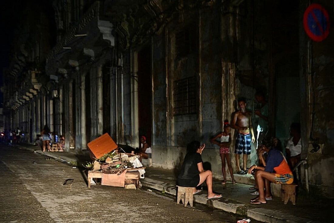 Cubanos conversam à noite em uma rua durante um apagão nacional causado por uma falha na rede em Havana em 18 de outubro de 2024.