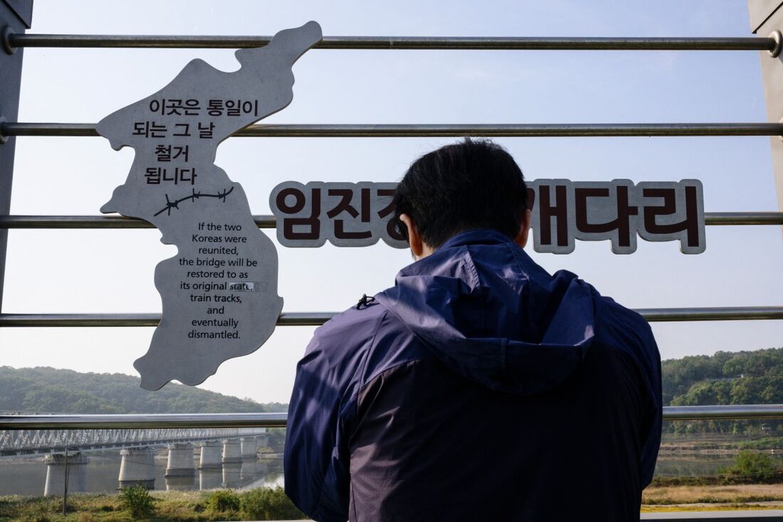 Um homem tira fotos de alguns dos pilares danificados restantes da Ponte Dokgae, antiga ferrovia que conectava as margens norte e sul do Rio Imjin, mas foi destruída durante a Guerra da Coreia