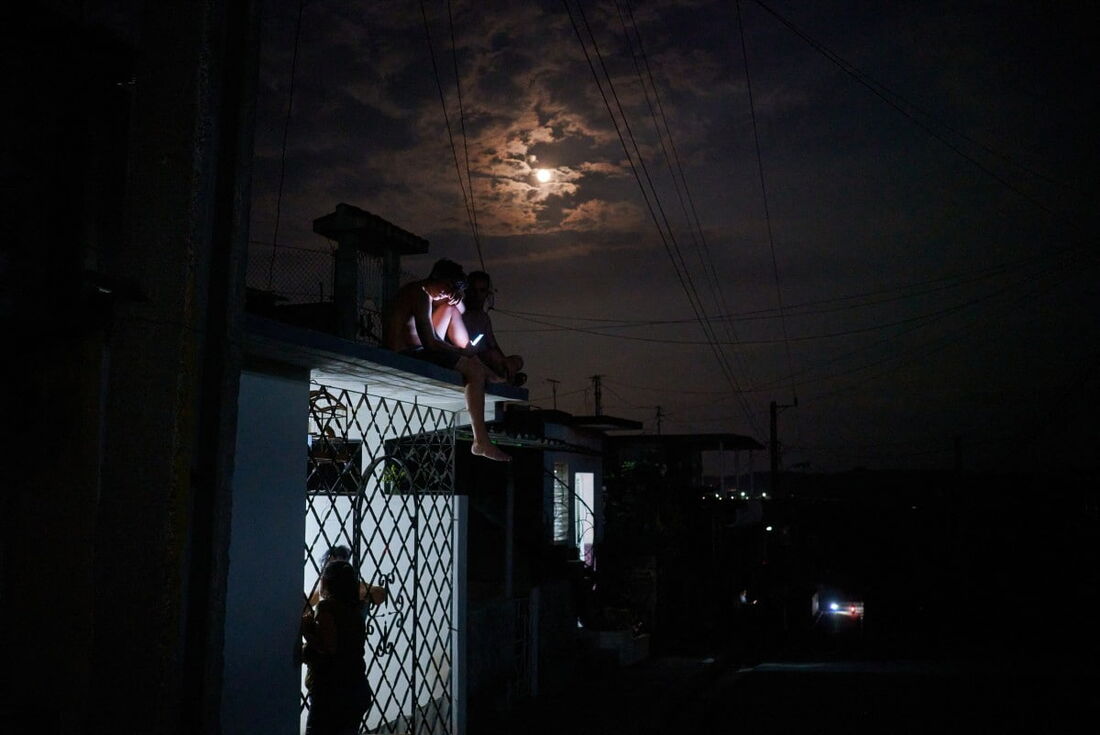  Moradores do bairro Naranjal Norte tentam obter conexão com a internet e ar fresco em uma noite quente de verão no telhado de uma casa durante uma queda de energia noturna de 6 horas na província de Matanzas, Cuba, em 22 de maio de 2024.