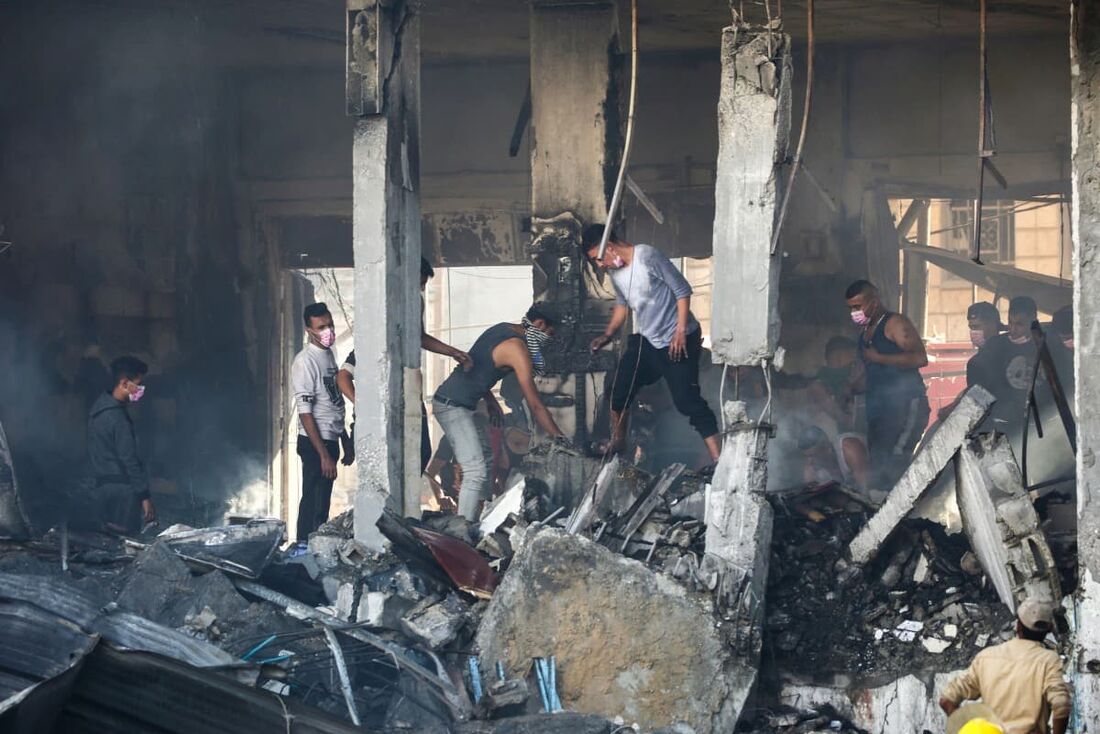 Palestinos verificam o prédio destruído do Maghazi Camp Services Club após um ataque israelense ao campo de refugiados de Maghazi na Faixa de Gaza