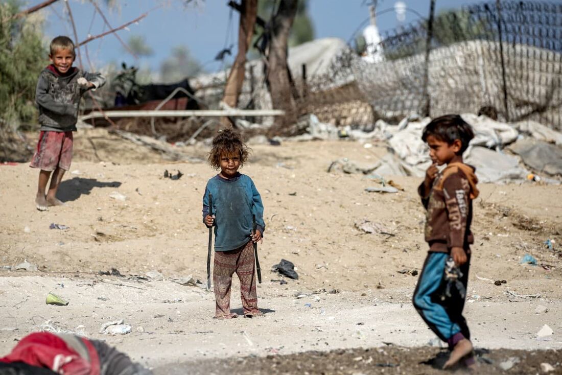 Crianças brincam juntas na poeira perto de barracos em Khan Yunis, no sul da Faixa de Gaza