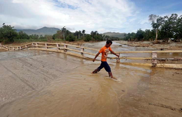 Homem cruza uma rua inundada dias após a passagem do furacão Oscar em Guntánamo, Cuba