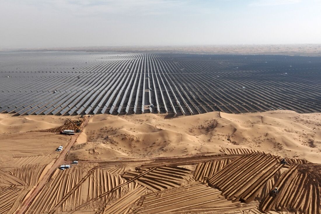 Esta foto tirada em 9 de dezembro de 2023 mostra veículos preparando terreno para novos painéis solares na Nova Base de Energia do Deserto de Ningxia Tengger, na região de Ningxia, norte da China