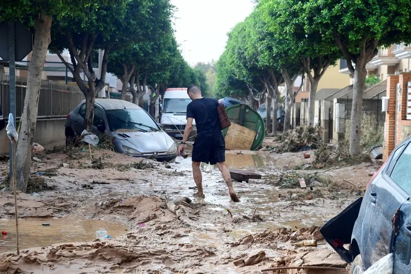 Homem caminha em rua coberta de lama em uma área inundada em Picanya, perto de Valência, leste da Espanha