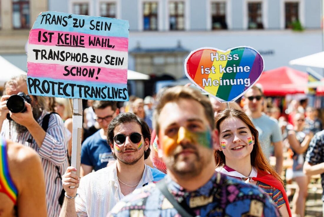 Participantes seguram cartazes com os dizeres "Ódio não é uma opinião" (R) e "Ser trans não é uma escolha, mas ser transfóbico é (uma escolha)!" durante o evento anual de orgulho LGBTQ Christopher Street Day (CSD) em Pirna, leste da Alemanha