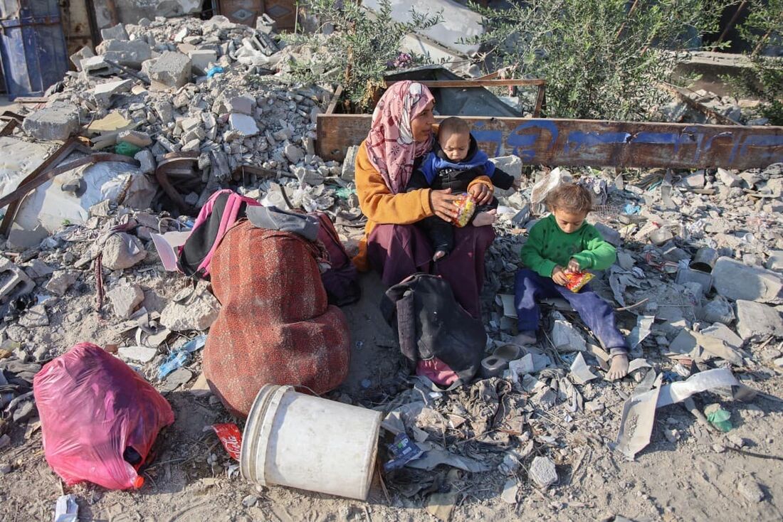 Uma mulher descansa com seus filhos enquanto palestinos deslocados fogem de Beit Lahia, no norte da Faixa de Gaza