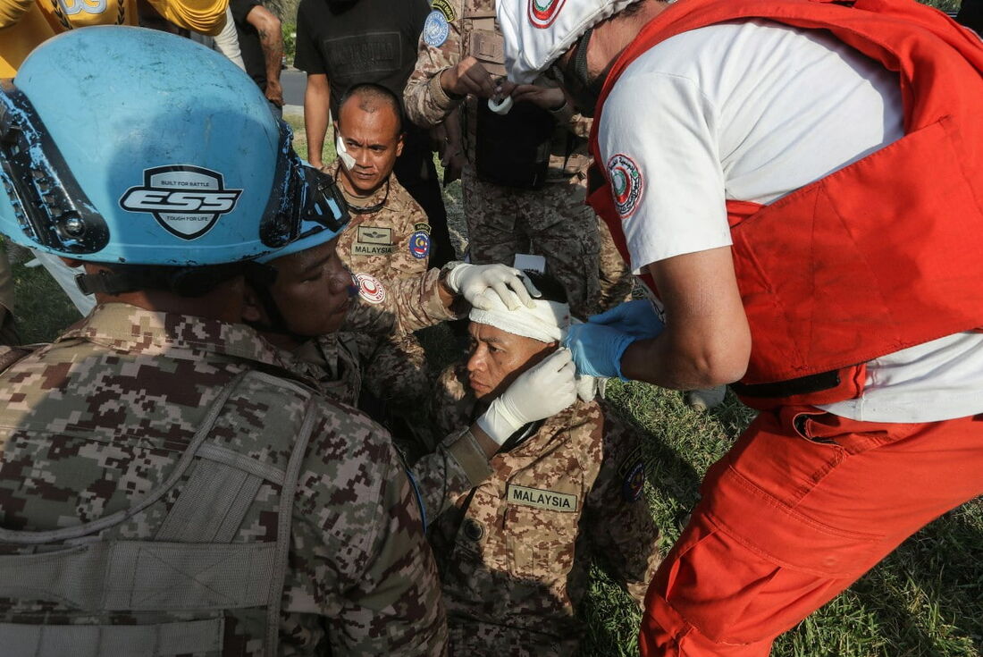 Um socorrista e um membro do batalhão malaio da Força Interina das Nações Unidas no Líbano (UNIFIL) tratam do ferimento de um colega soldado.