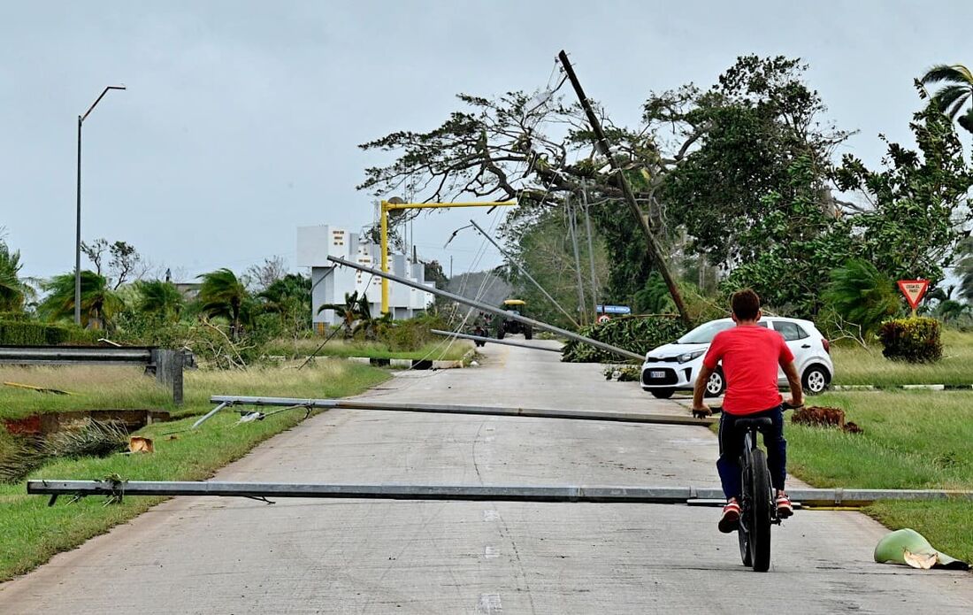 Moradores passam por árvores caídas e linhas de energia após a passagem do furacão Rafael em Artemisa, Cuba