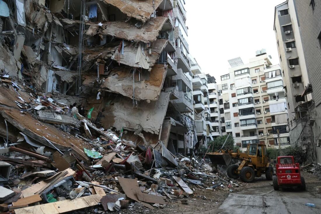 Trabalhadores limpam escombros no local dos ataques aéreos israelenses noturnos que atingiram a área de Tayouneh, nos subúrbios de Beirute