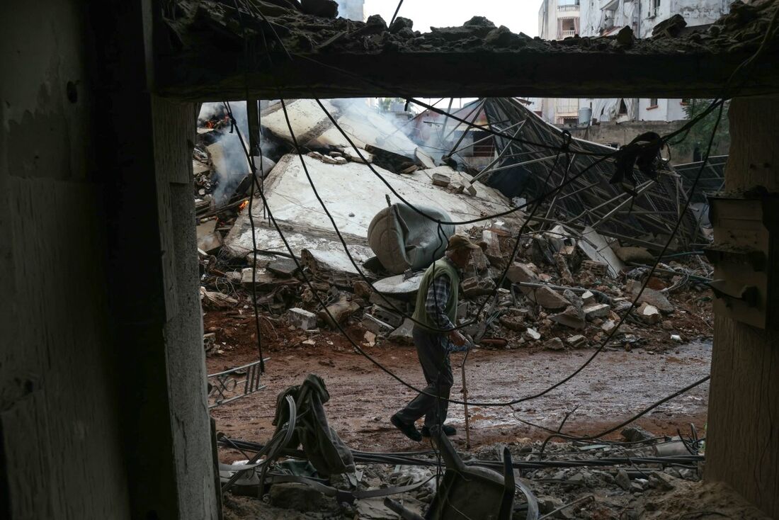 Homem passa pelos escombros de um prédio destruído por um ataque aéreo israelense, no bairro de Shiyah