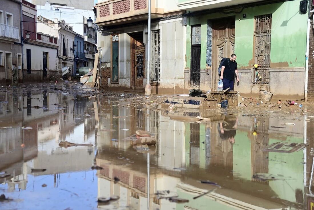 Um homem caminha em uma rua inundada em Paiporta, na região de Valência, leste da Espanha, em 4 de novembro de 2024, após inundações devastadoras e mortais