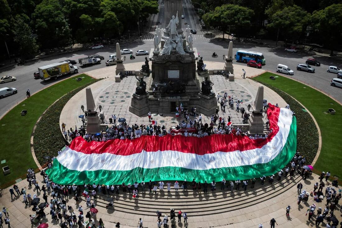  Membros da Associação Nacional de Magistrados e Juízes Distritais seguram uma enorme bandeira mexicana durante um protesto após a aprovação pelo Senado da reforma judicial proposta pelo governo na rotatória Angel de la Independencia, na Cidade do México