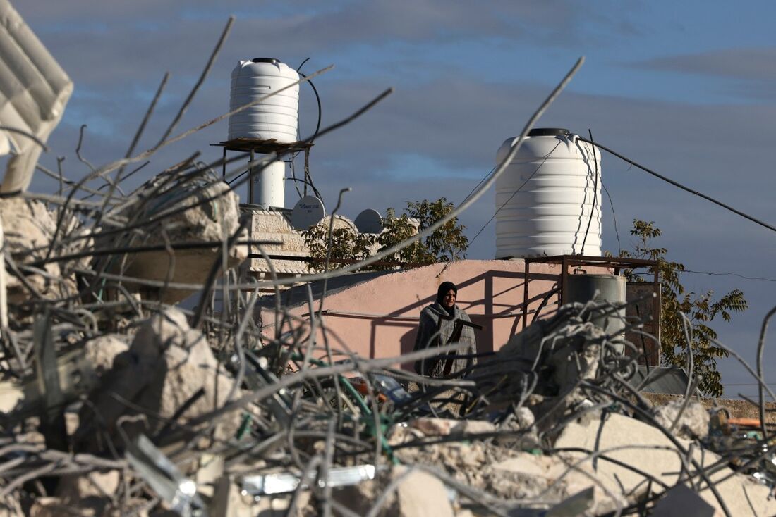 Mulher palestina olha para os restos de uma casa, depois que ela foi demolida por escavadeiras israelenses, na vila de Idna