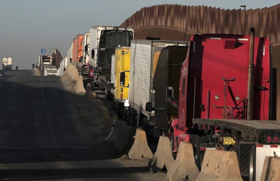 Caminhões esperam em uma fila para cruzar para os EUA ao lado do muro da fronteira no porto comercial de Otay em Tijuana, estado de Baja California, México.